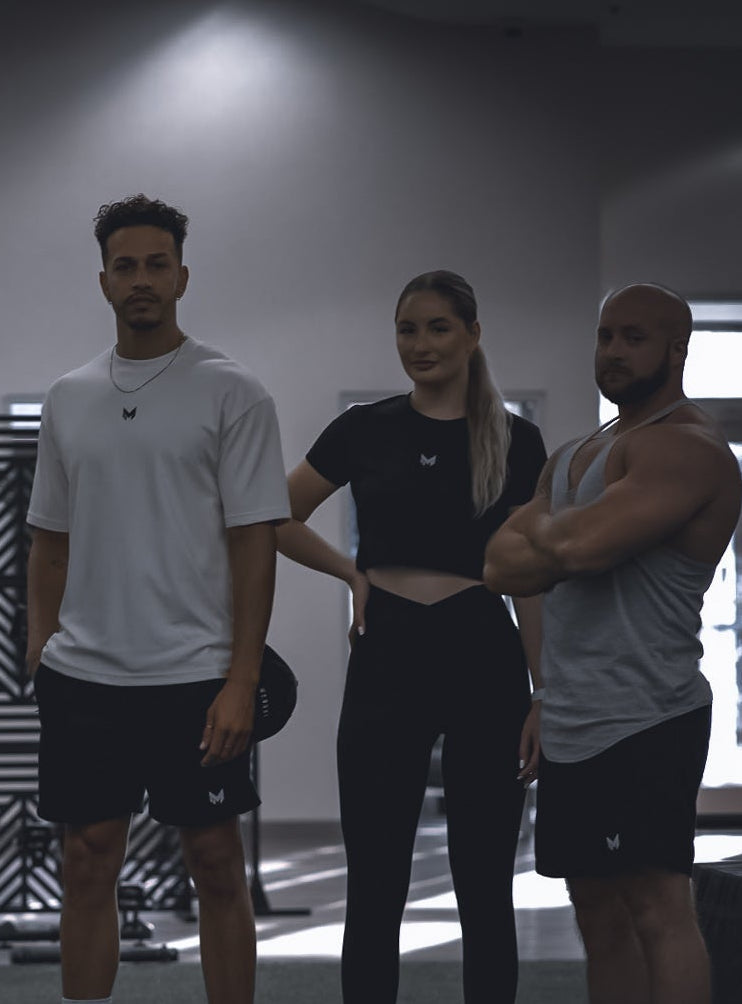 Three people standing together in a gym setting
